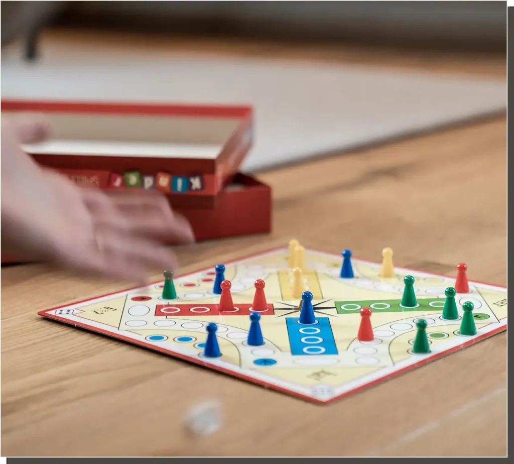 Rozłożona na drewnianej podłodze dziecięca gra planszowa „Ludo” z kolorowymi pionkami i pudełkiem w tle